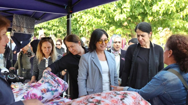Kayapınar Belediyesi eşbaşkanları ve konukların Park 75'teki Peyas festivalinde bir kadın üreticinin stantındaki ürünleri incelemesi