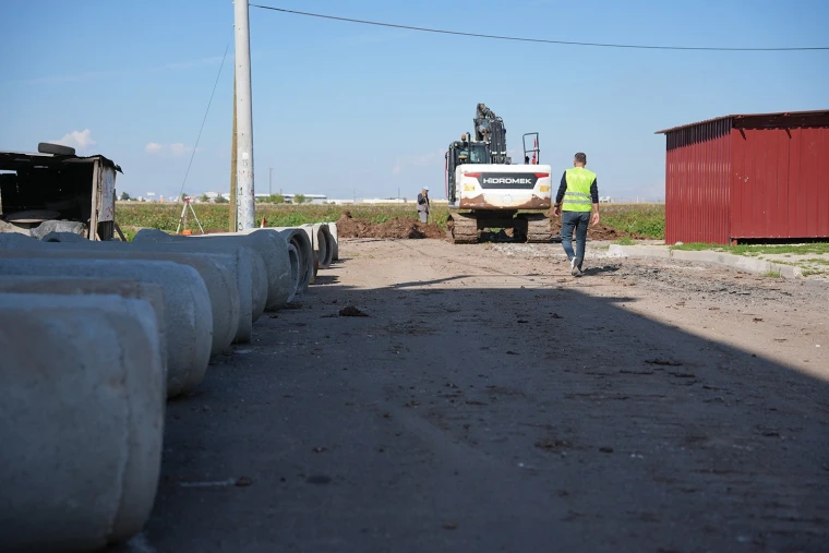 DİSKİ çalışanı Çelikevler'de kazılan kanala yerleştirilecek beton yağmur suyu borusunun yanında